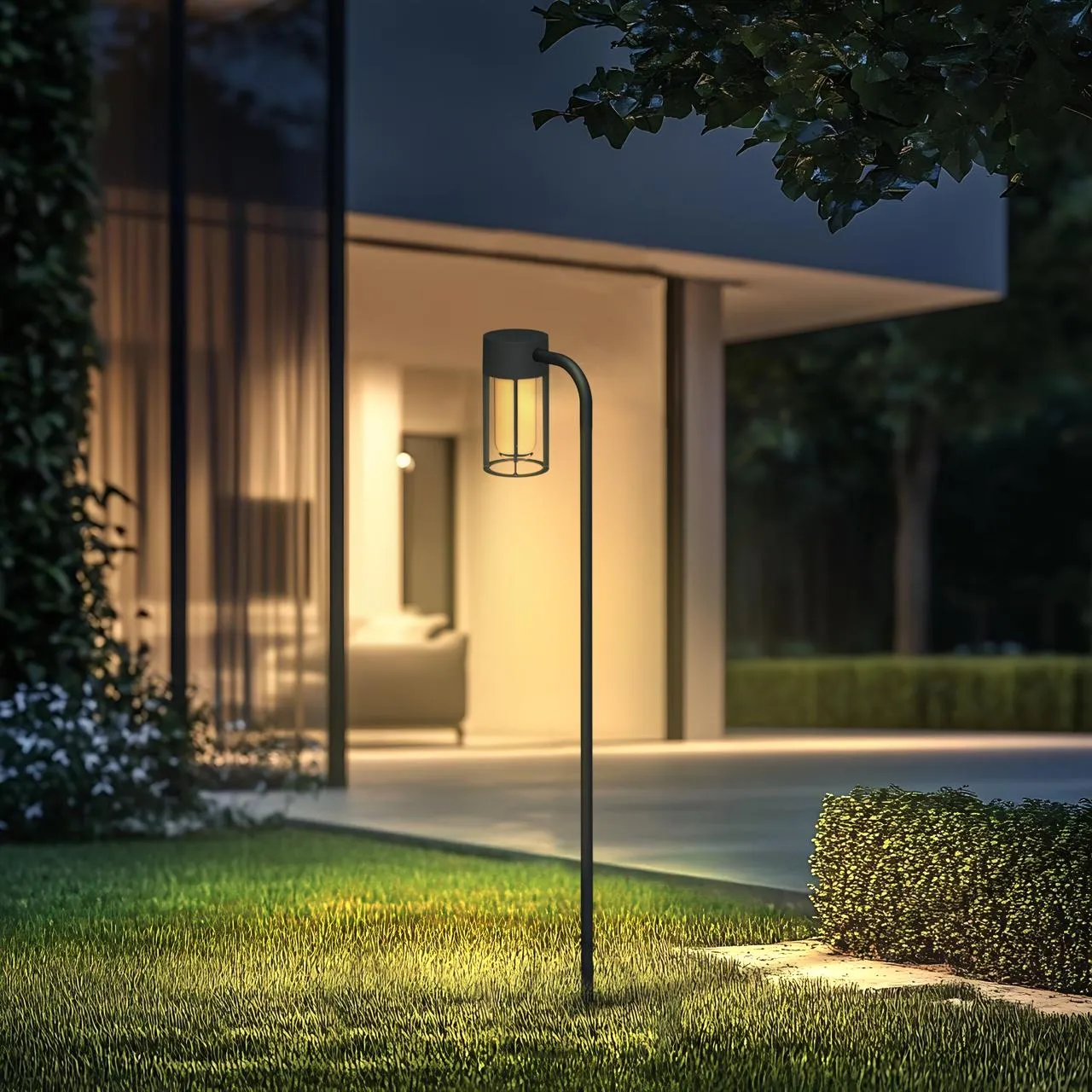 Curved-arm bollard with a caged glass lantern beside a house entrance at dusk