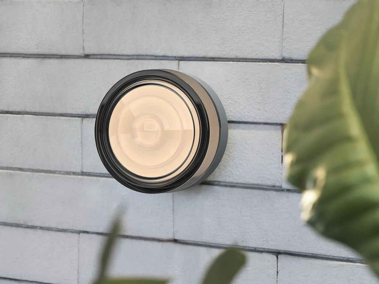 Round surface-mounted disc light casting a warm pool of light on a brick wall